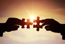 two puzzle pieces being held up against the sun