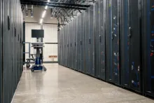 Gang zwischen hohen Server-Racks in einem Rechenzentrum mit moderner IT-Infrastruktur und industrieller Beleuchtung.