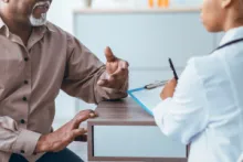 Männlicher Patient und Ärztin im Gespräch.