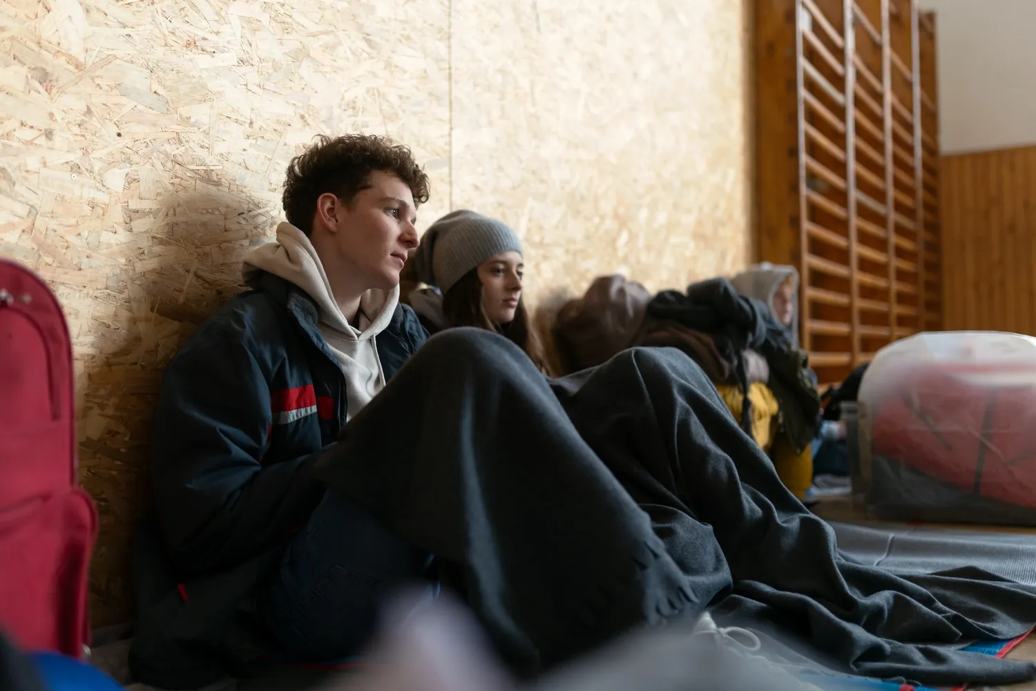 Menschen sitzen auf Boden in Turnhalle