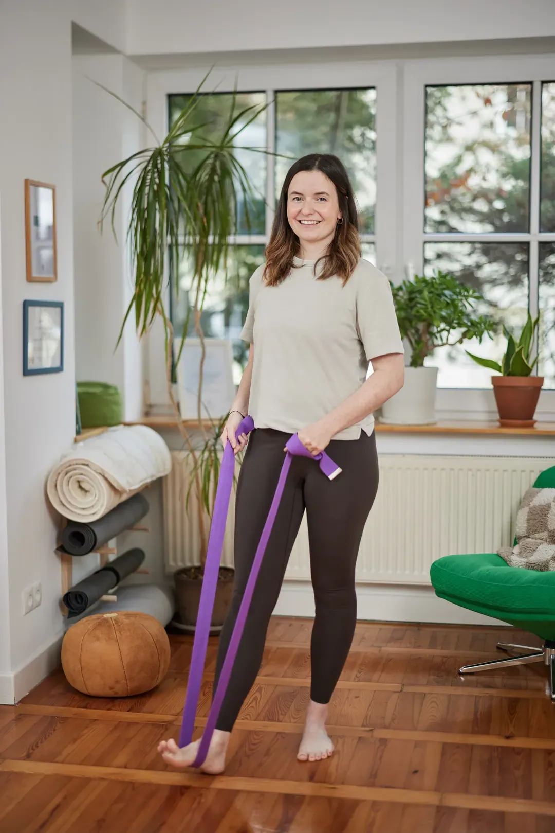 Frau trainiert mit einem Gymnastikband in einem Wohnraum.