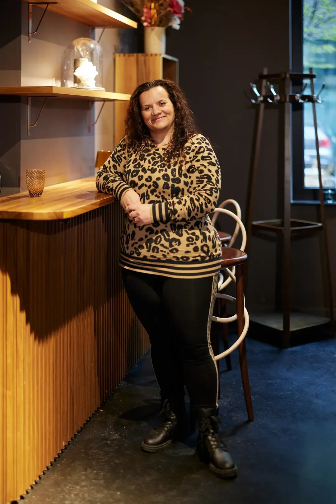 Frau steht an der Theke in einem dunkel beleuchteten Café.